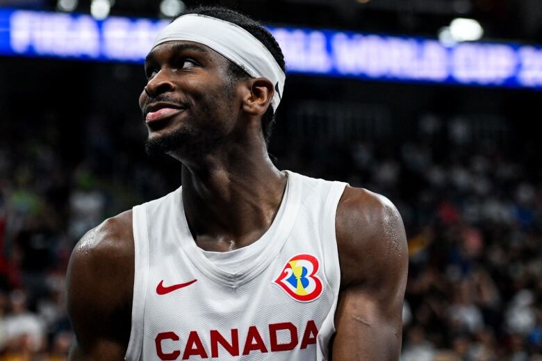 A men's basketball player looks on while smiling during a game.