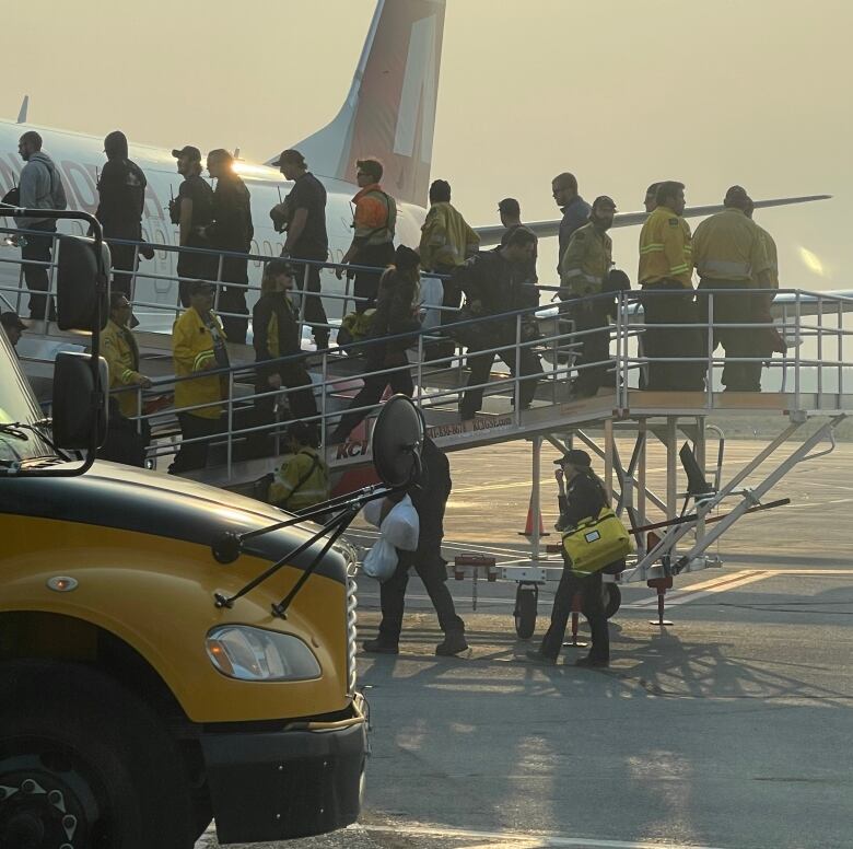 Men in work clothes on the ramp to a plane. 