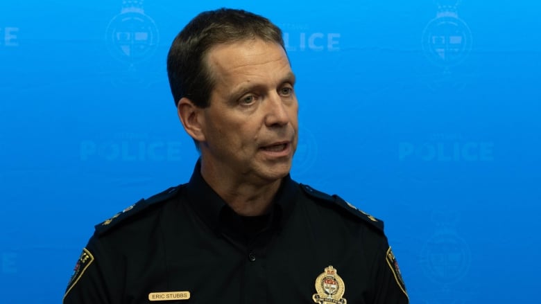 A police officer speaks at a news conference in front of a blue backdrop.