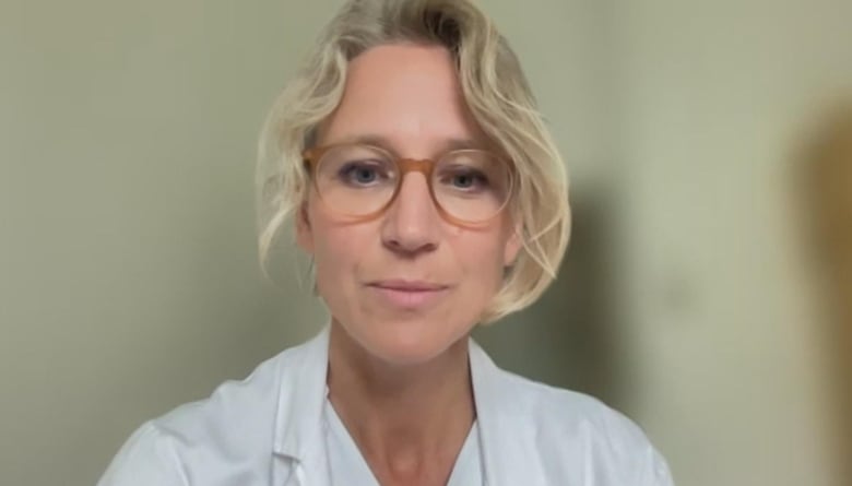 A woman in a white lab coat looks at the screen.