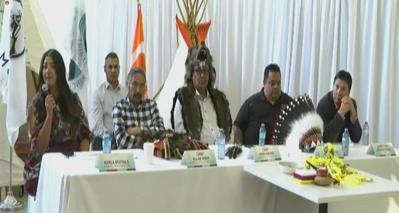 First Nations leaders sit in a row at a table.