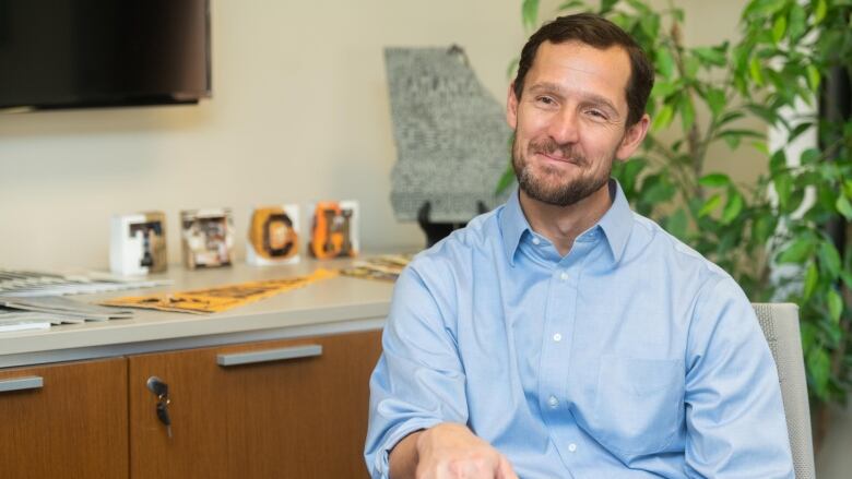 Man sitting down wearing a blue button down shirt. 