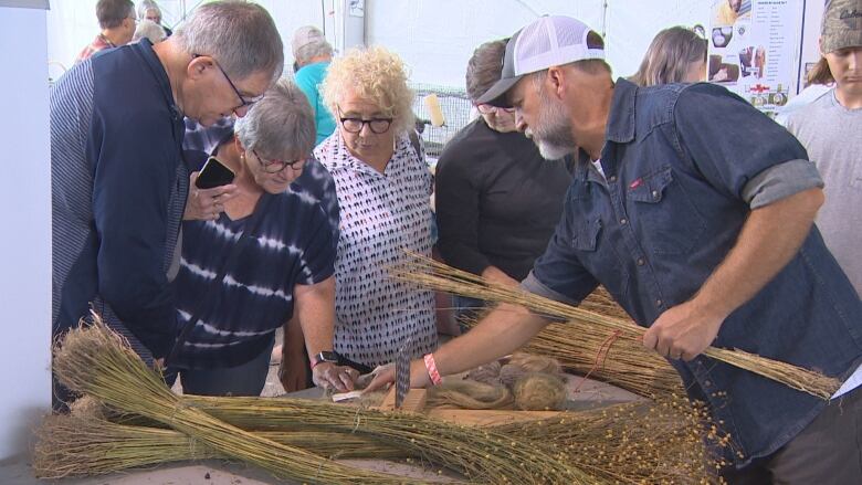 People stand around a table with raw fibres sitting on top.