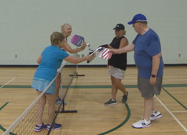 Players tap racquets at the end of a pickleball game 