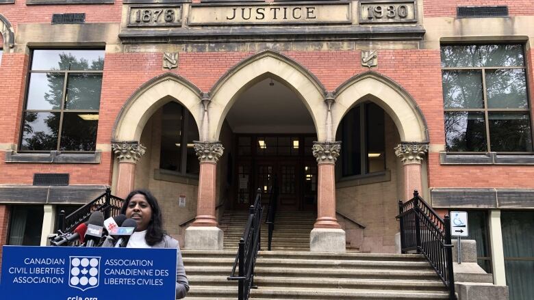 Woman speaking at podium, justice building in the background