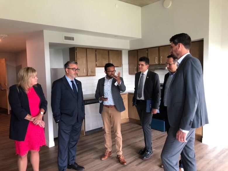 A group of people stand in an unfurnished apartment