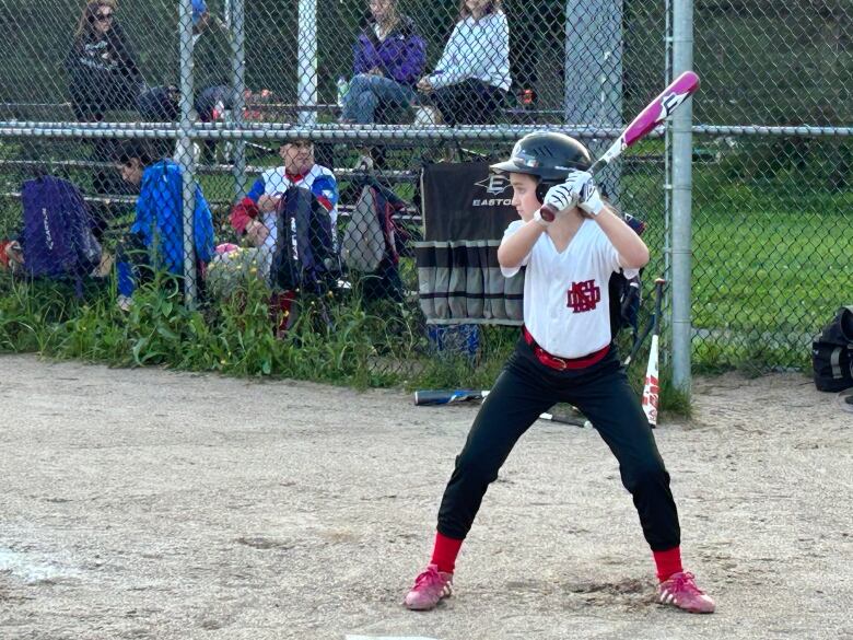 Girl stands confidently at bat.