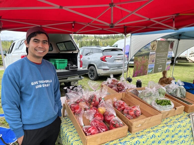 A man stands beside a table selling produce.