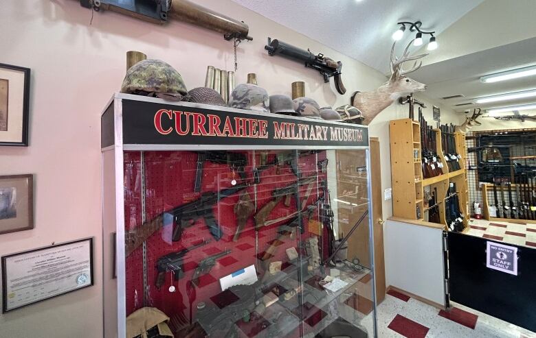 A glass display case shows antique guns