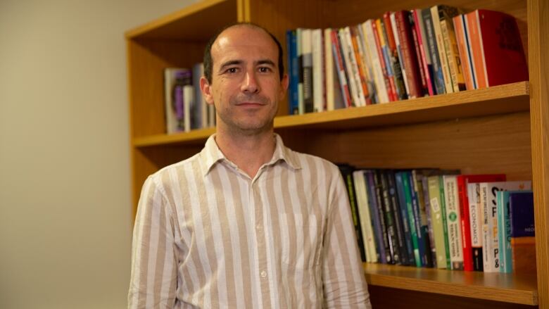 A person stands in front of a bookshelf.