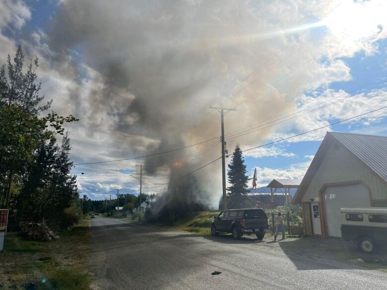 Smoke billows up from a lot on a small town street. 