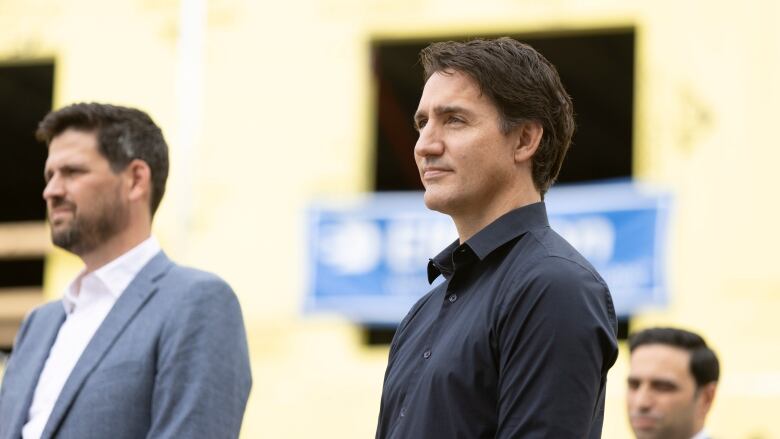 Two men stand in front of a construction site.