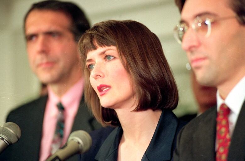 A woman with hair past her chin speaks into a microphone.