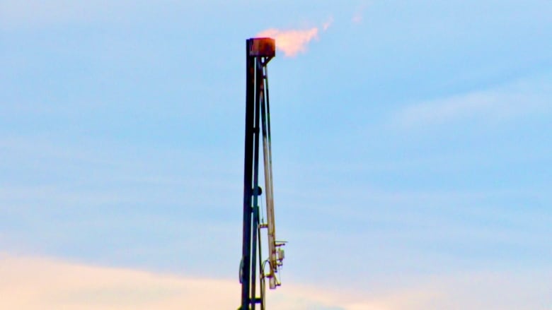 At an oil production site, a flame is shown at the top of a flaring pipe.