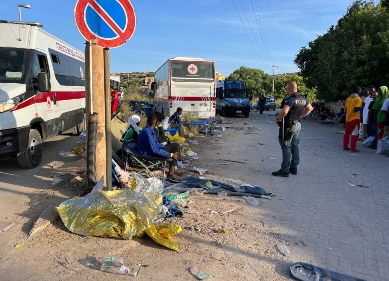 A police offers oversees migrants sleeping on the street.