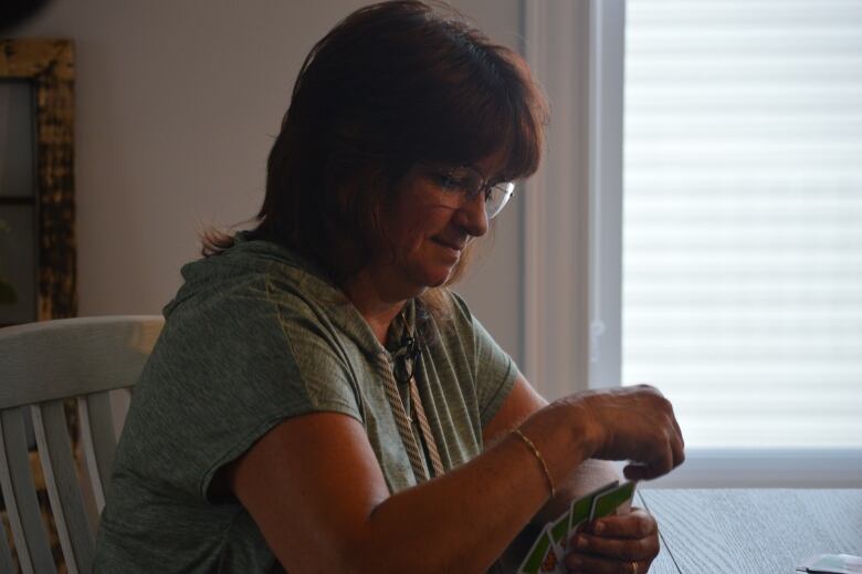 A woman sits at a table playing cards