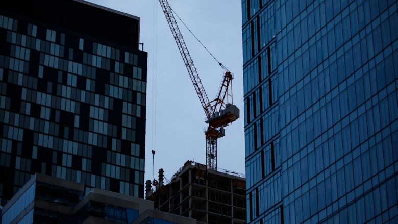 A crane pictured in the background with two condo buildings in the foreground.