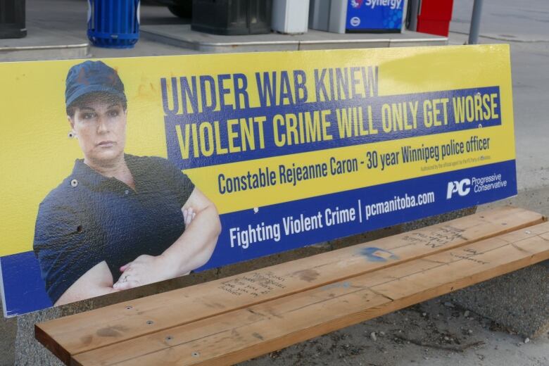 A woman looks stern with her arms crossed in a bus bench ad that reads in part, 'Under Wab Kinew violent crime will only get worse.'