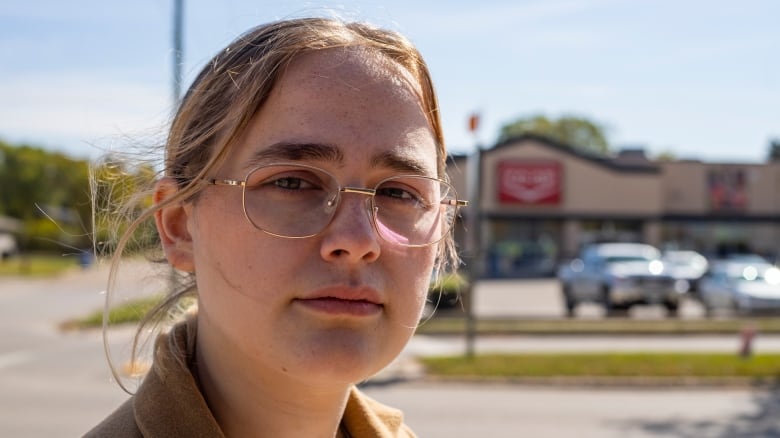 A woman with blond hair and glasses stares at the camera.