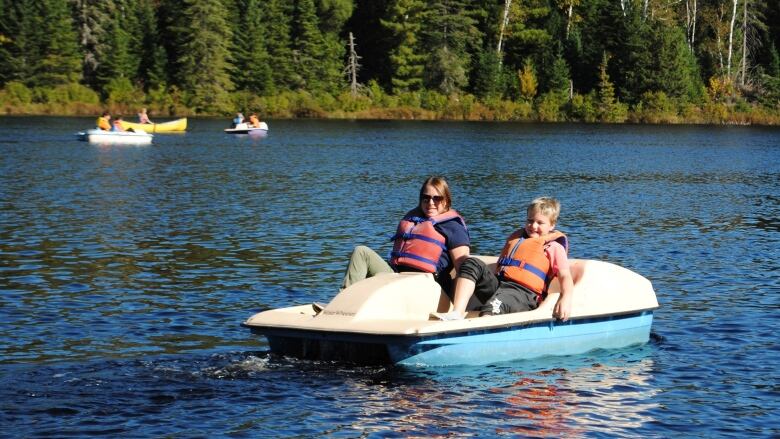 A woman and boy are in a pedal boat.