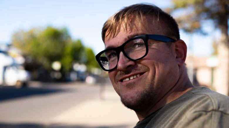 A man wearing glasses smiles.