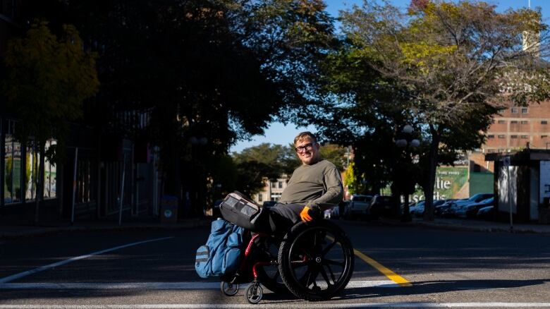 A man in a wheelchair sits in a pedestrian crossing.