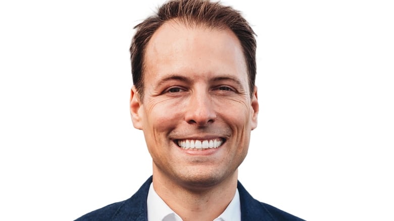 A caucasian man smiles in a headshot.