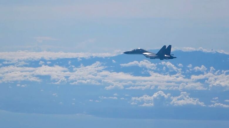 A warplane flies above the clouds.