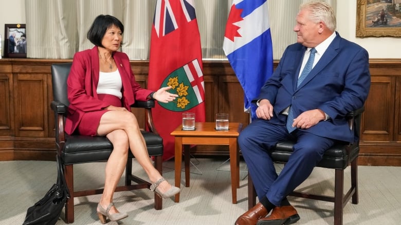 A man and woman sit in chairs talking.