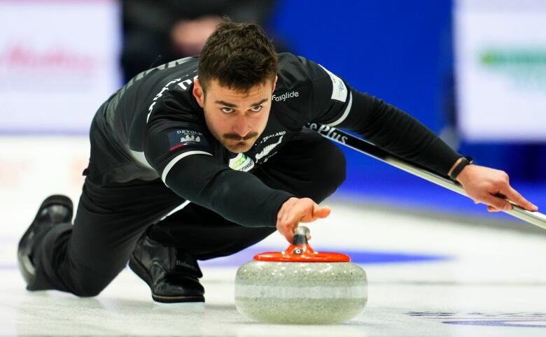 A man throws a curling rock. 