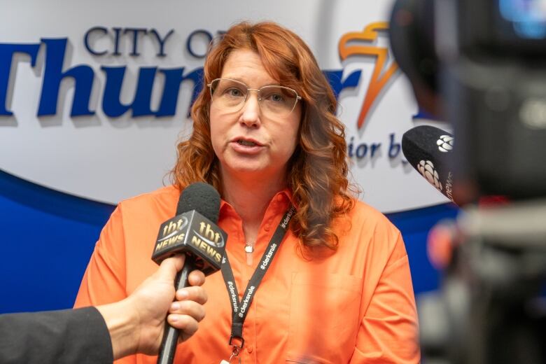 A woman answers questions from reporters.