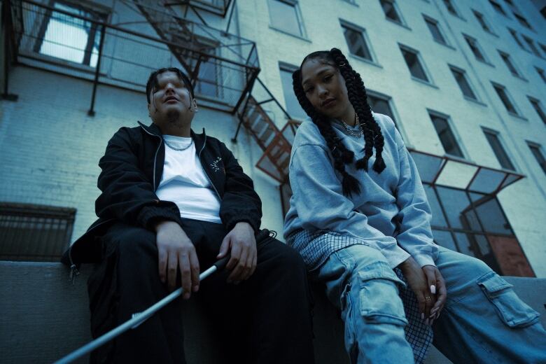 Mattmac, left, Mariame, right, both sitting along a building of the streets of Winnipeg. 