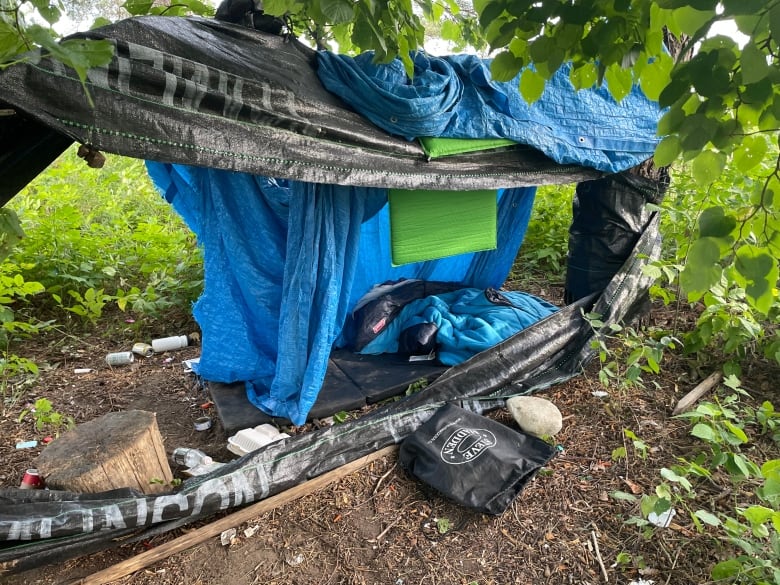 A tarp over a sleeping bag and other belongings in a field in late summer.