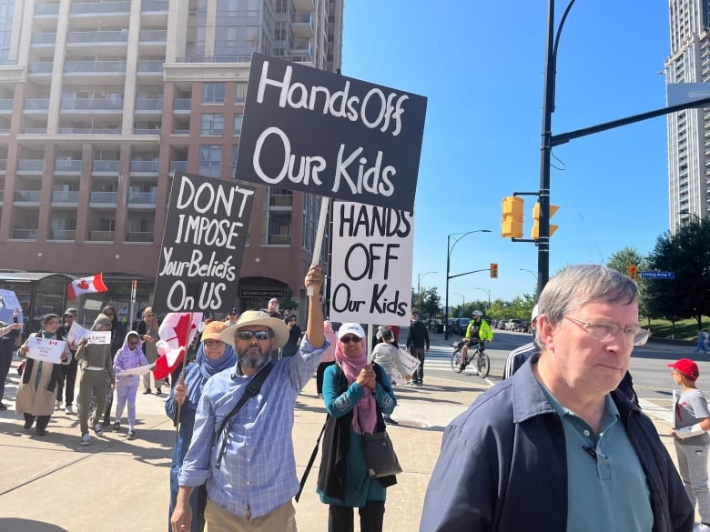 Protesters hold signs at an event in Mississauga.