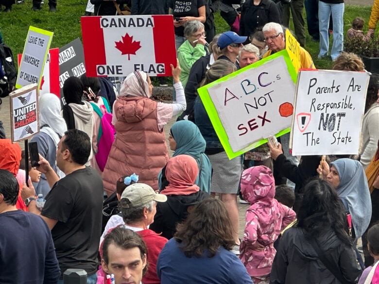 A group of people holding signs are shown.