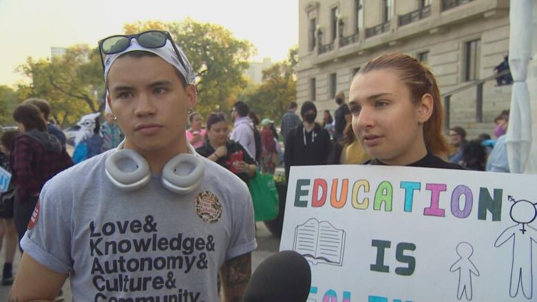 Two people attend a protest outside a legislature.