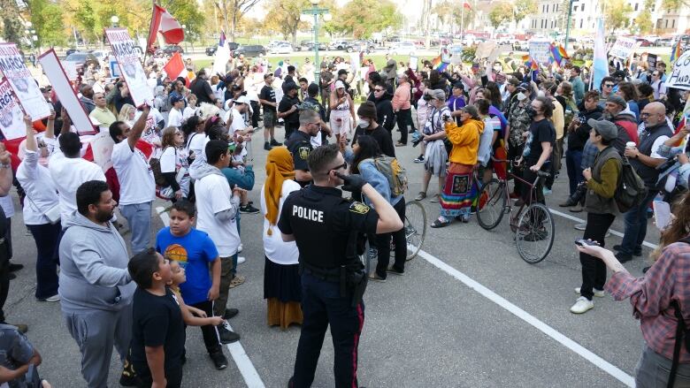 Hundreds of people participating in a protest and counter protest come face to face outside a legislative building.