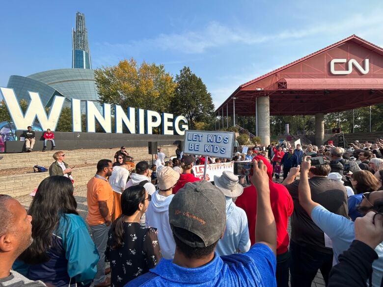 People hold up signs including one that says 'let kids be kids.'