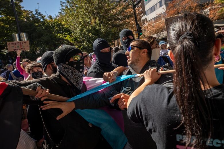 People confront each other, one side in black face masks