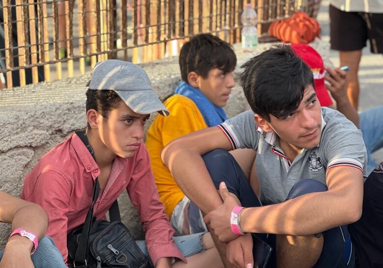 Young men wait on the street.