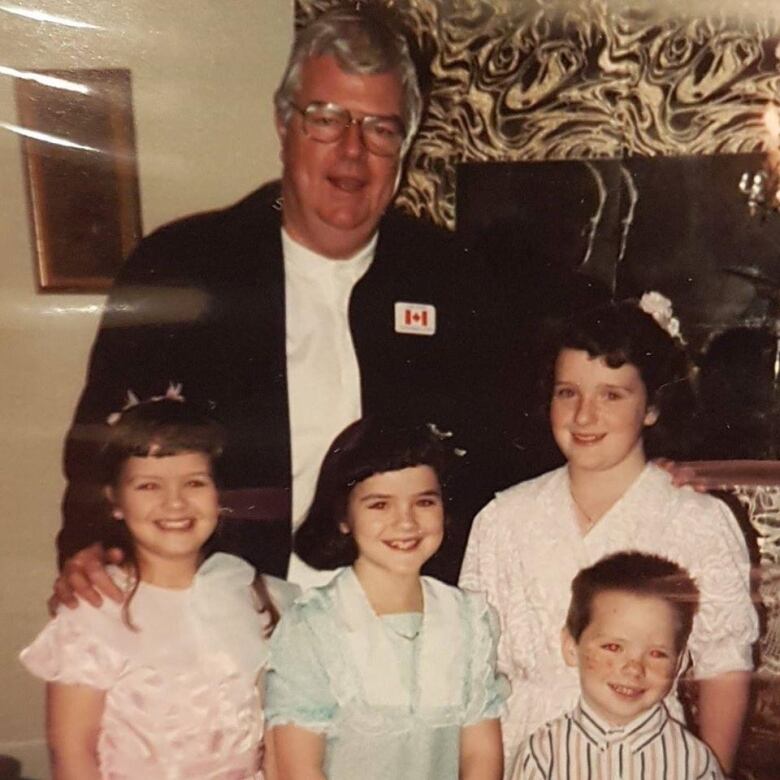 A man standing next to four children, 3 girls, 1 boy. 