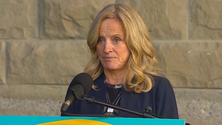 A woman stands in front of podium.