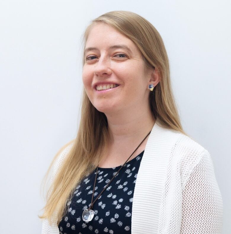 Profile photo of a Caucasian adult woman with long blonde hair wearing a black shirt and white cardigan