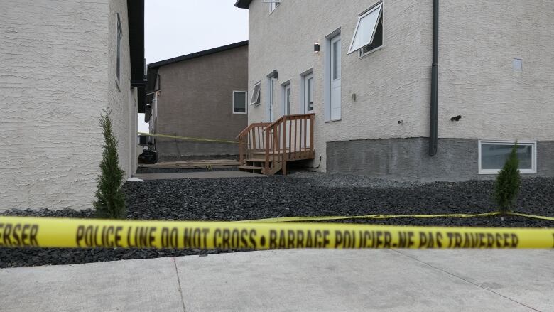 Yellow crime scene tape surrounds two homes. 