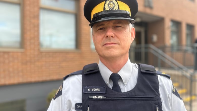 Cop with blue and yellow hat looks at camera  