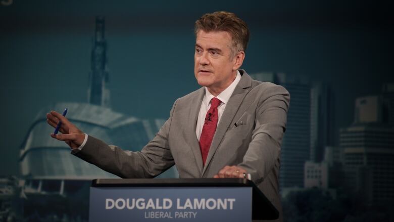 A man in a suit speaks at a podium.