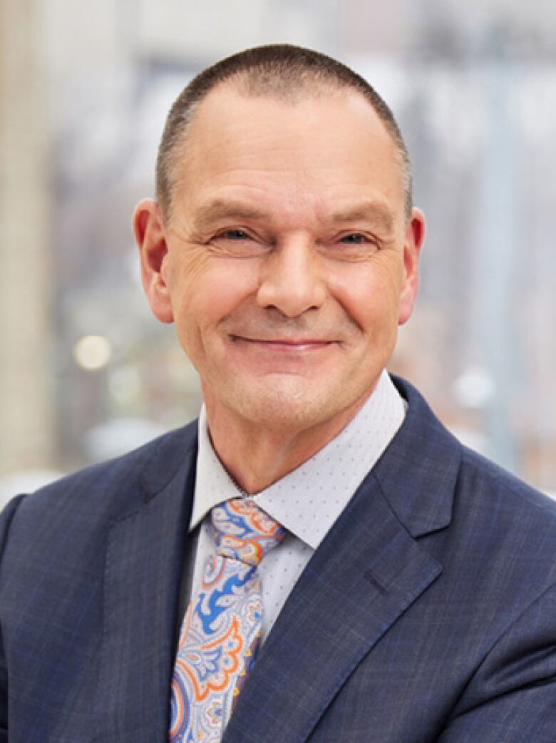 A smiling man dressed in a suit and tie.