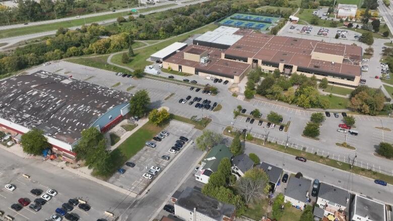 A view from above of an arena and school near a wooded area and creek.