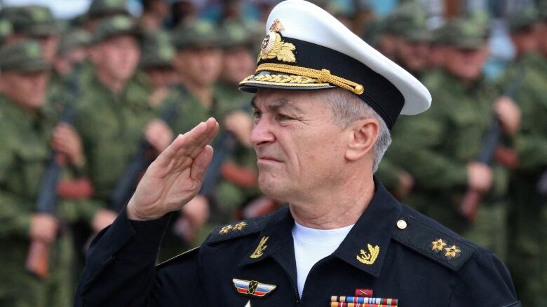 A Russian admiral in a white hat gives a salute.