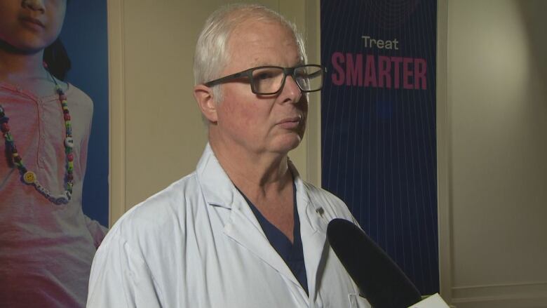 Surgeon stands in hospital hallway.